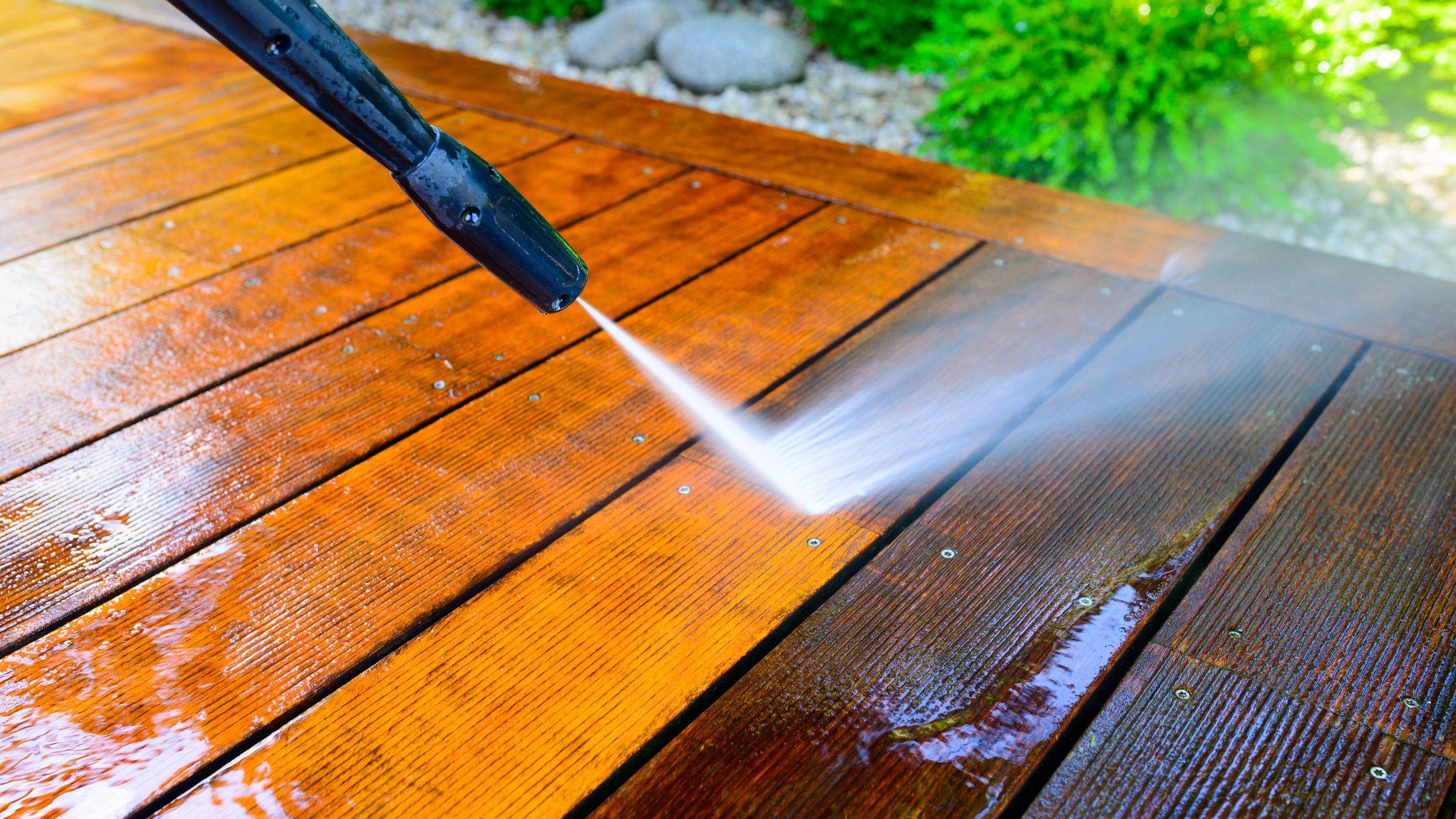 using a pressure washer to clean a wooden deck